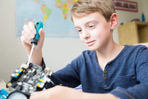 Boy Assembling Robotic Kit In Bedroom